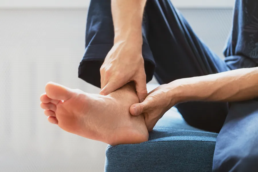 Person holding ankle area with both hands, representing ligament injury or joint instability - seeking platelet rich plasma treatment