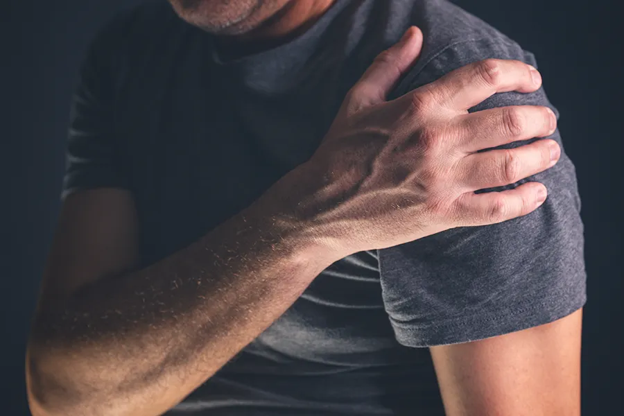 Man holding shoulder with pain, representing rotator cuff injury treated with platelet rich plasma injection