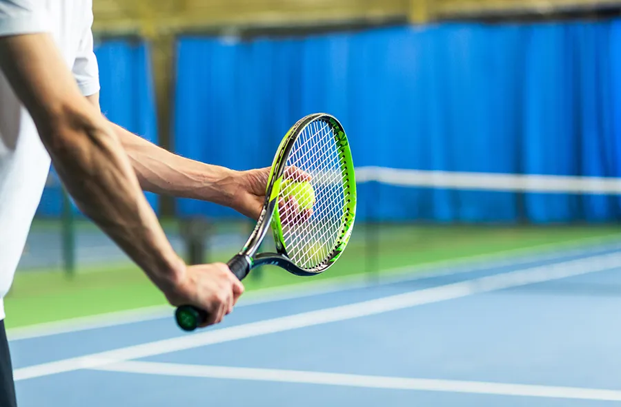Tennis player holding racket, representing repetitive strain treated with PRP for lateral elbow tendon injuries